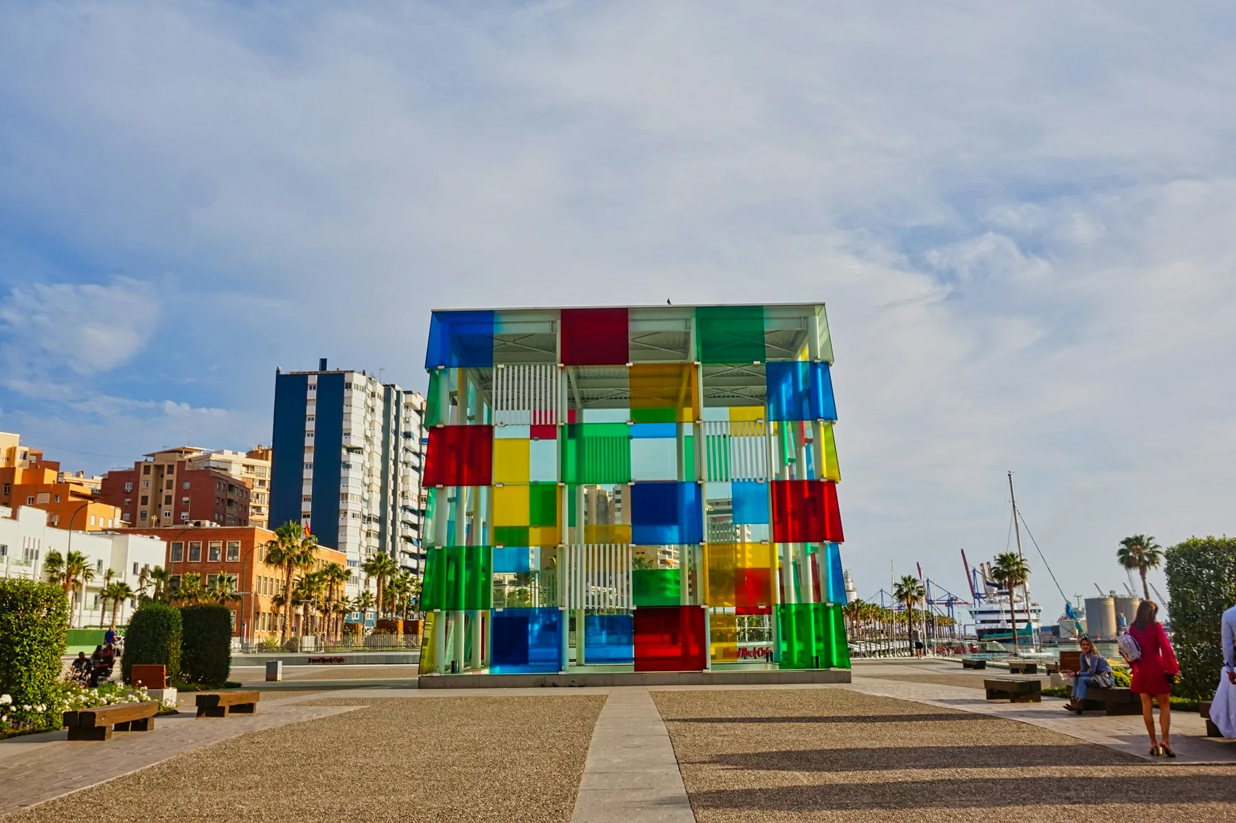 The coloured glass cube of the Centre Pompidou Málaga on the port promenade under a cloudy sky